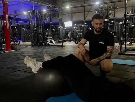 Ćwiczenie z piłką gimnastyczną na macie, Mateusz kontroluje wykonanie ruchu
